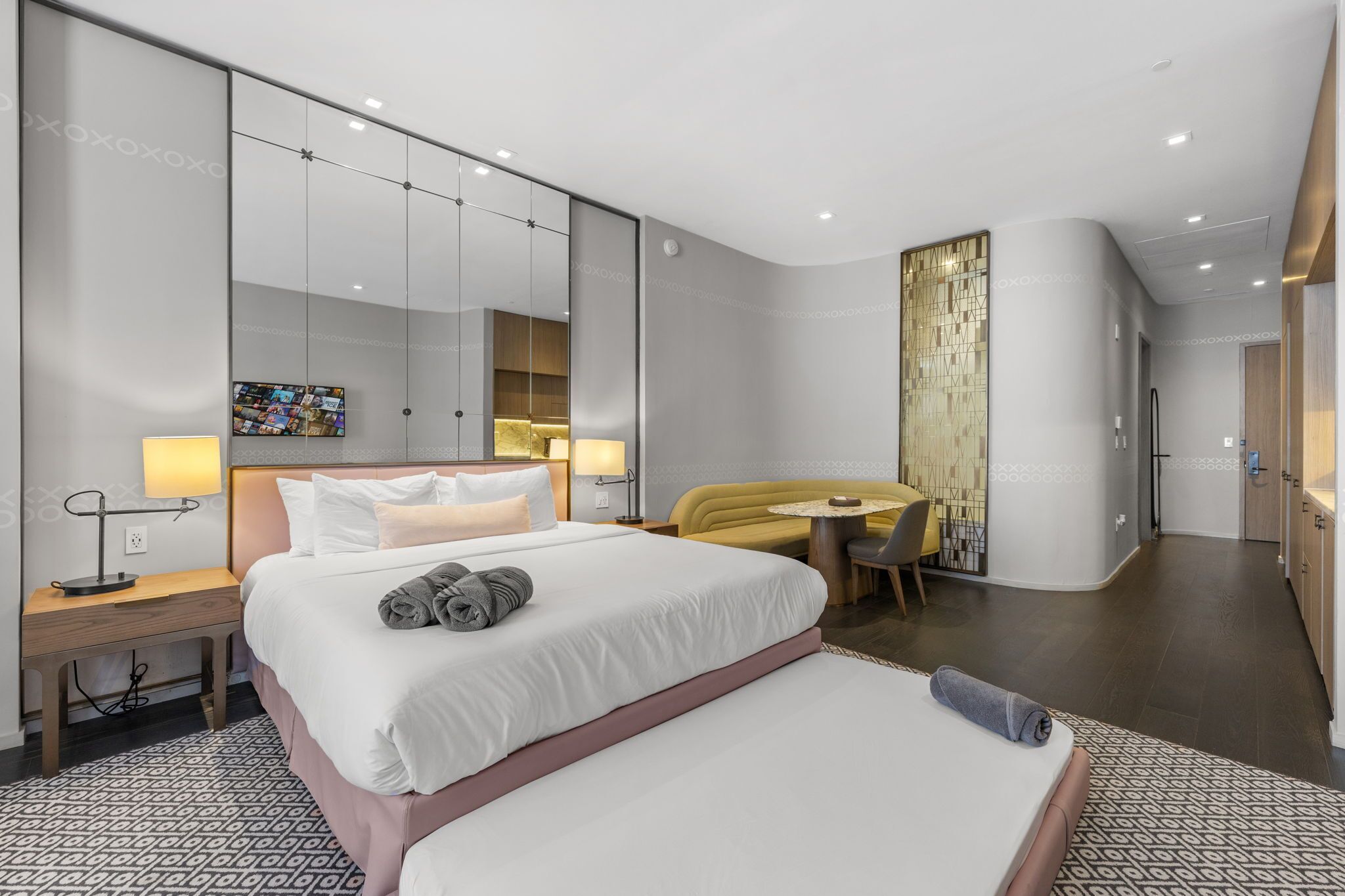 Une chambre d’hôtel moderne, dotée d’un grand lit, de tables de chevet, d’un bureau et d’une chaise.