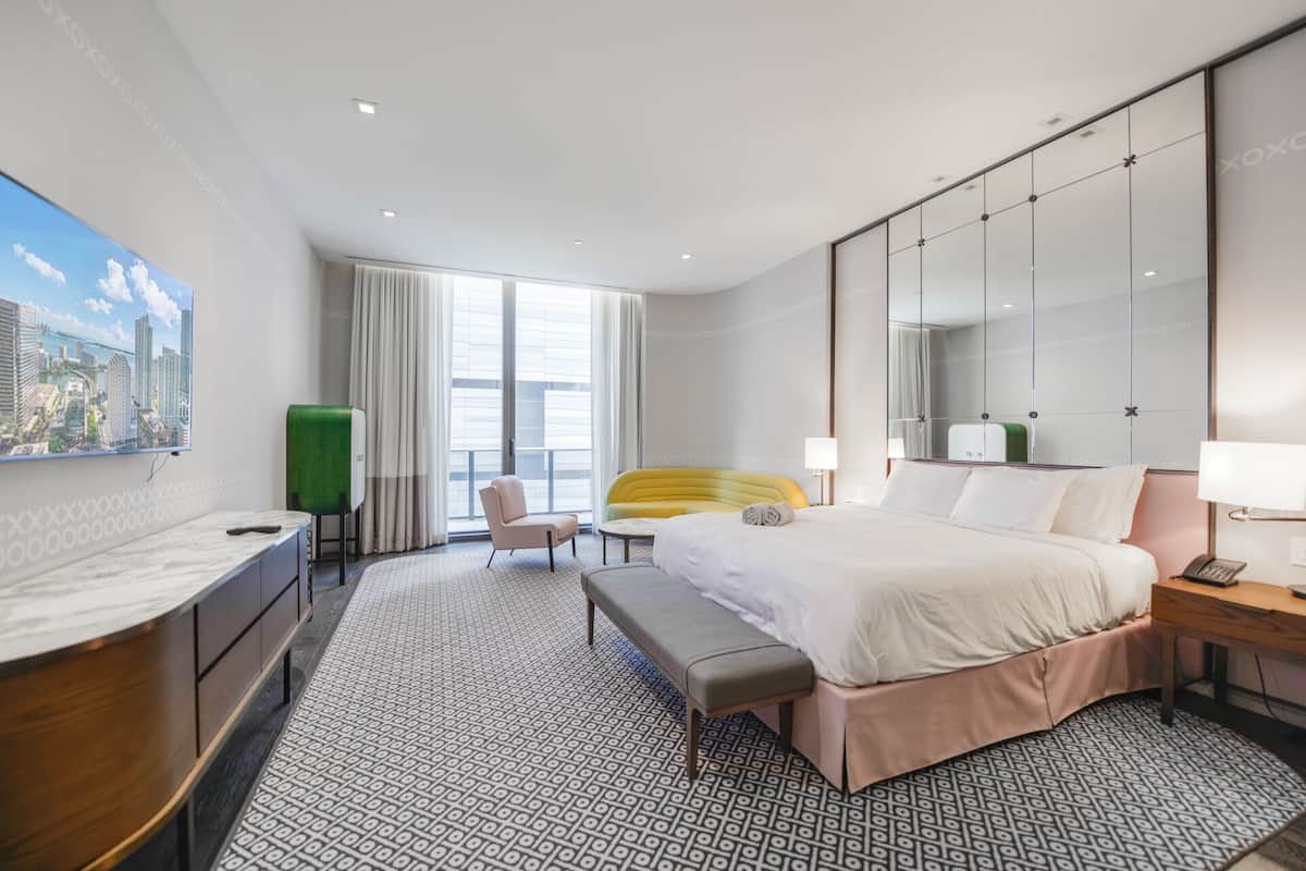 Une chambre d’hôtel moderne équipée d’un grand lit, d’un bureau, d’une chaise et d’un banc.