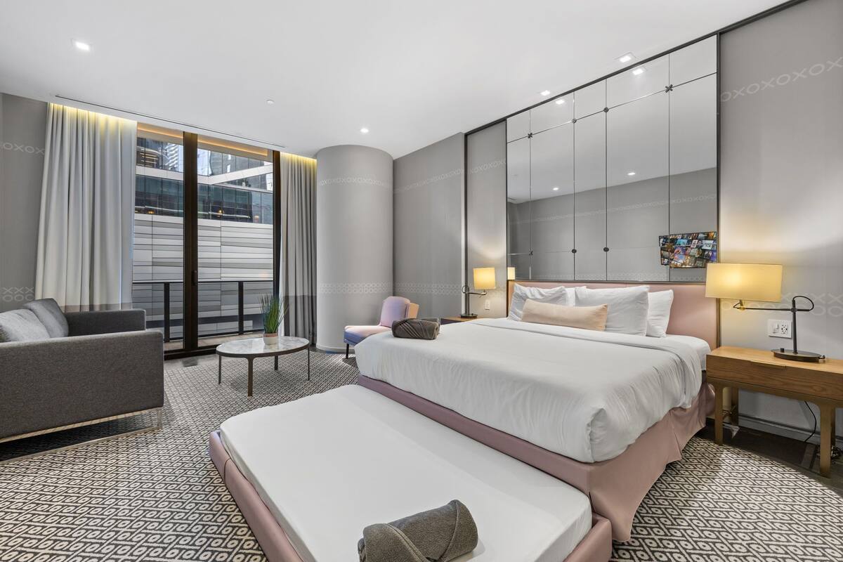 Une chambre d’hôtel moderne avec un grand lit, un canapé, une petite table et une chaise.
