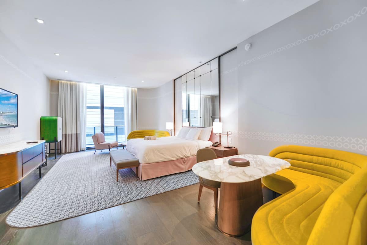 Une chambre d’hôtel moderne équipée d’un lit, d’un bureau, d’une chaise, d’un canapé et d’une petite table.