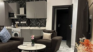 Un salón moderno con sofá, una mesa de centro y una cocina al fondo.