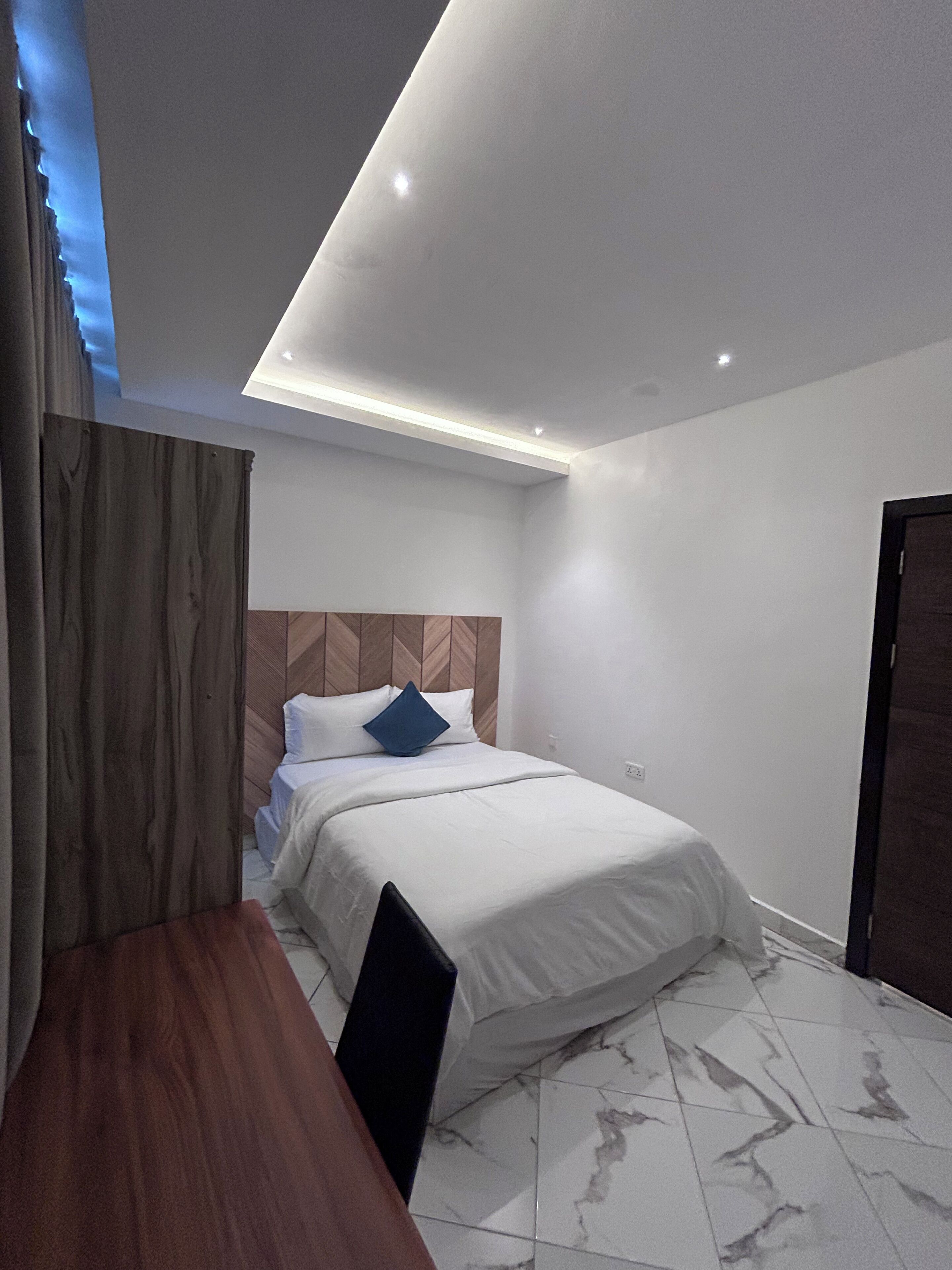 Een moderne slaapkamer met een bed, een houten hoofdeinde en een bureau.