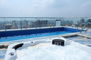 A rooftop pool with a hot tub, clear pool rules sign, and city views. - BOT PROPERTIES (Accra)