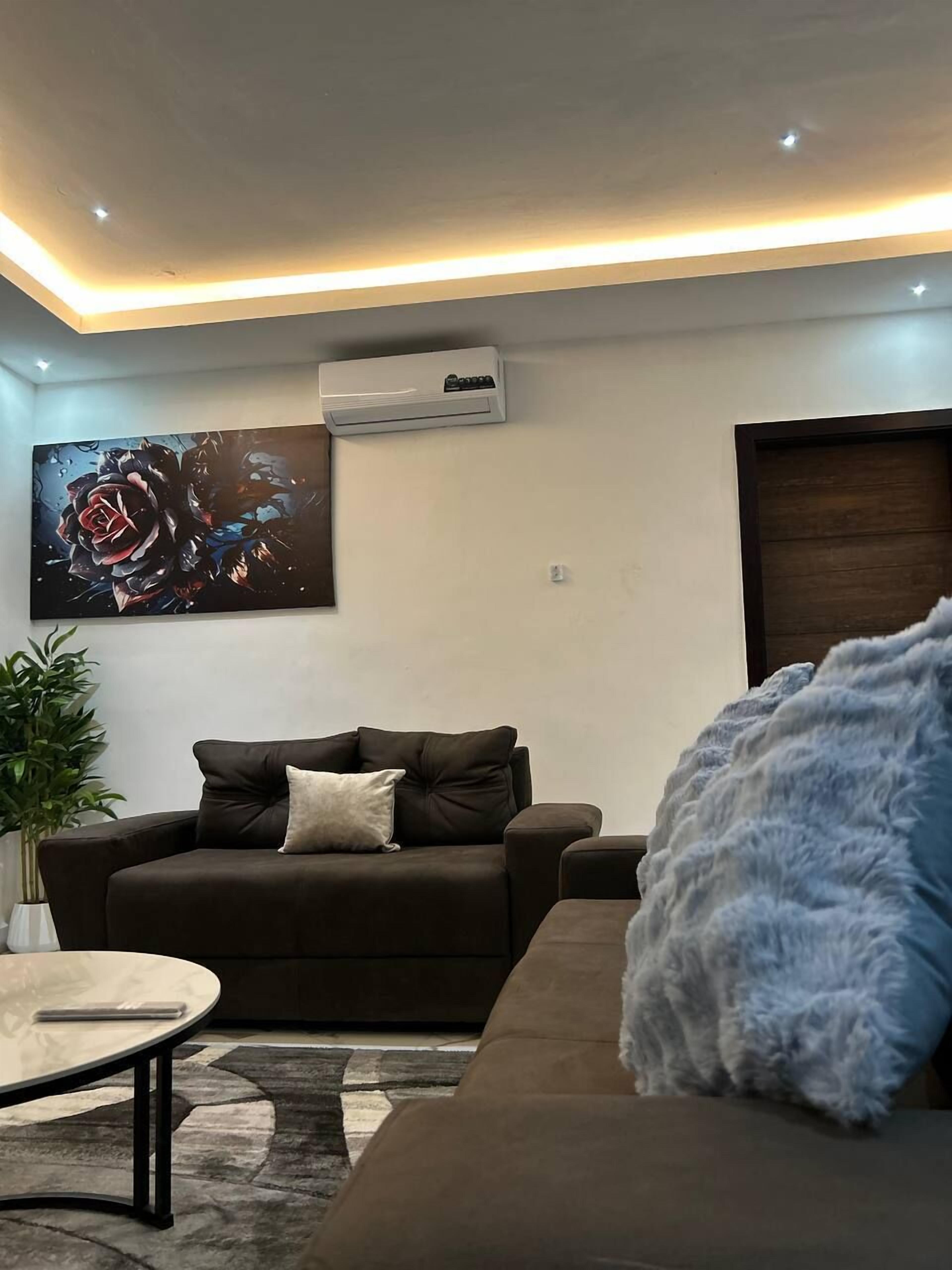 A modern living room with a dark brown sofa, a round coffee table, and a large abstract painting on the wall.