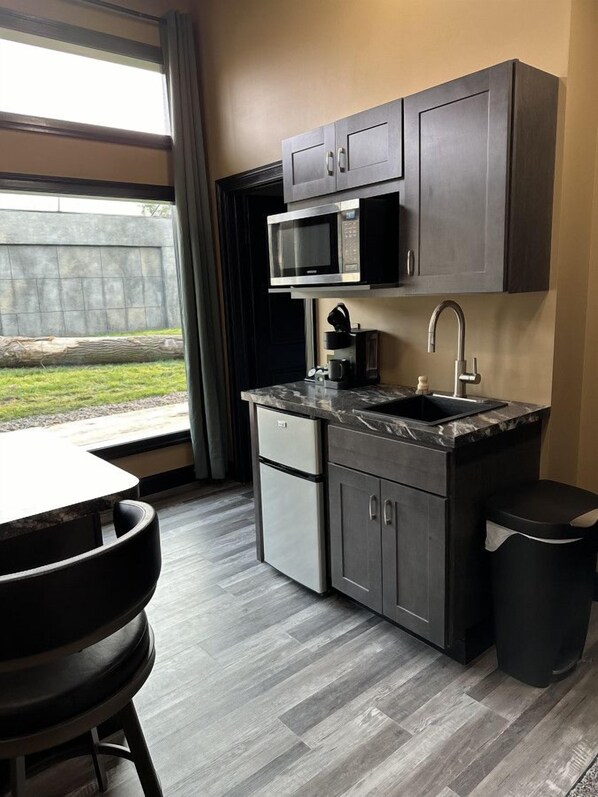 A compact kitchen with dark cabinetry, a built-in microwave, a coffee maker, and a sink.