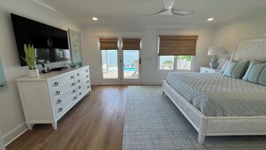 Un dormitorio con cama, cómoda, televisor y ventilador de techo.