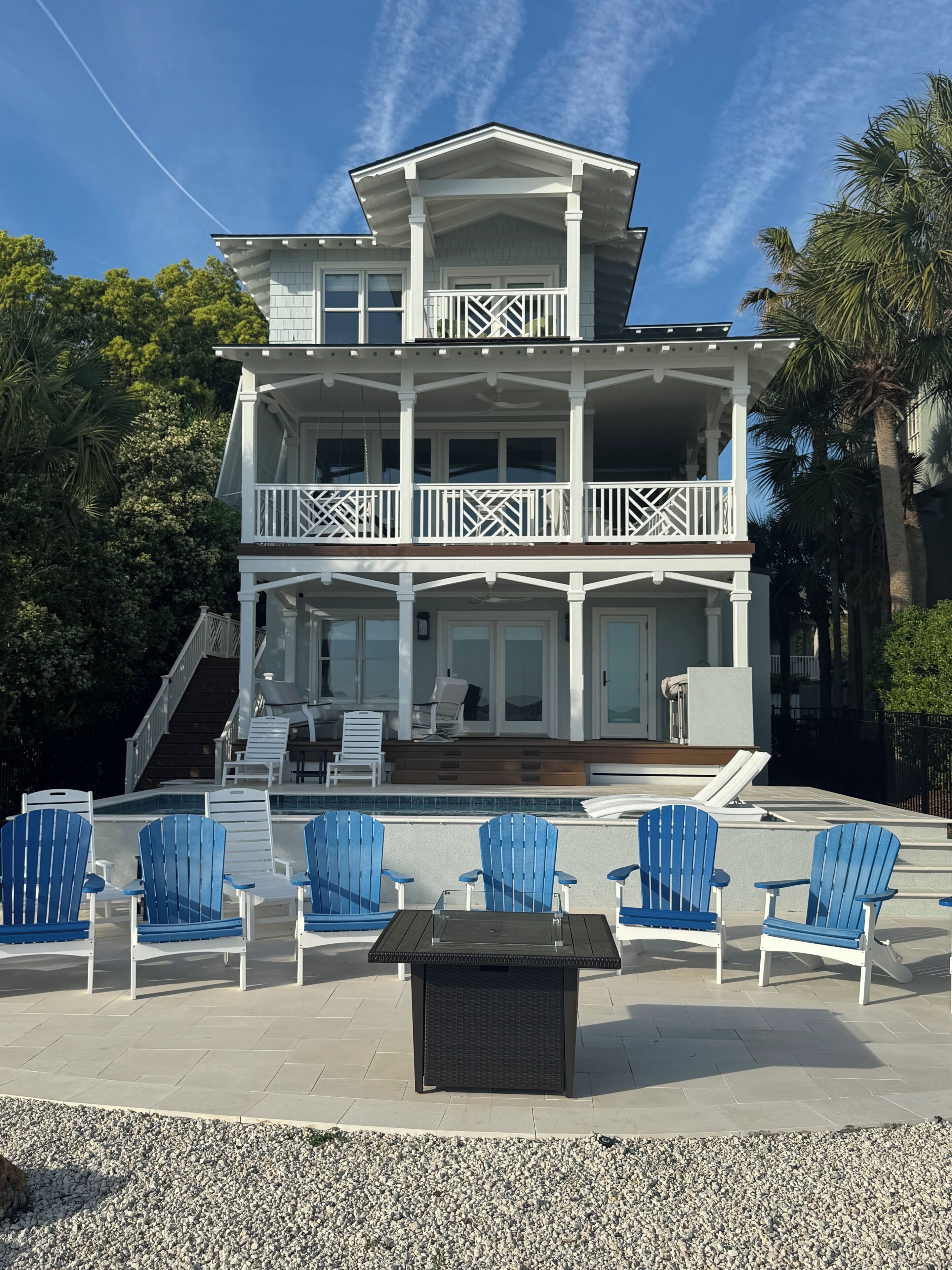 A two-story house with a balcony, outdoor seating, and a pool.