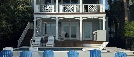 A two-story house with a balcony, outdoor seating, and a pool.