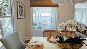 Comedor con una mesa dispuesta para dos personas, con individuales tejidos y un centro de mesa de orquídeas blancas.