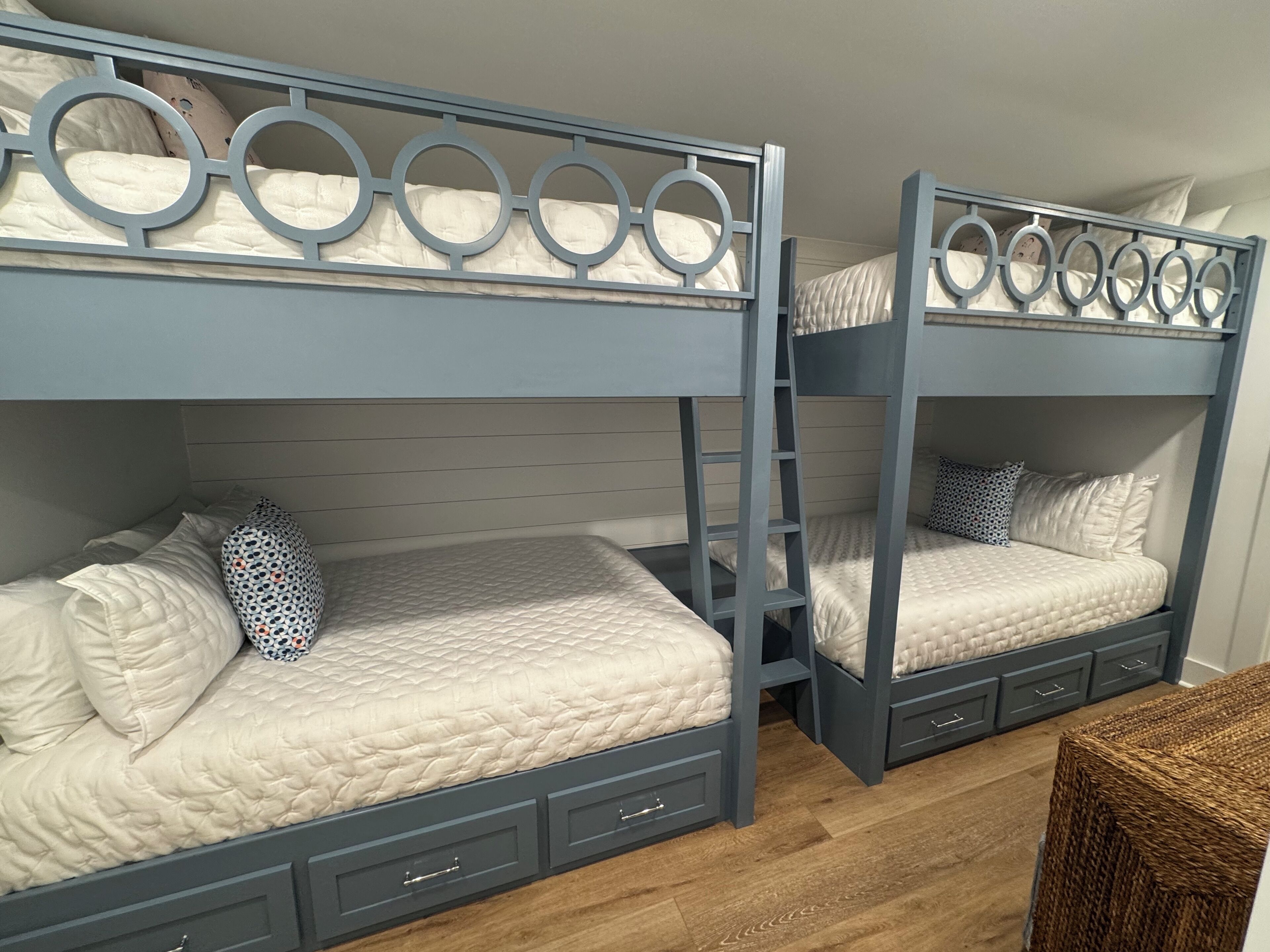 A room with bunk beds, each with a ladder, a headboard, and a pillow.