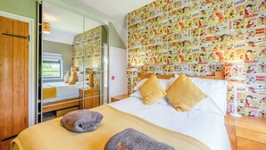 Une chambre d’hôtel avec un lit, une armoire, un miroir et un mur recouvert d’affiches de bandes dessinées.