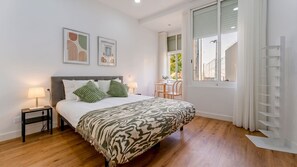 A hotel room with a bed, bedside tables, a window with curtains, and a view of the outside. - Charming 1Bdr Flat in Central Faro by Lovelystay (Faro)