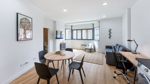 A modern living room with a dining area, a sofa, a TV, and a washing machine. - Charming 1Bdr Flat in Central Faro by Lovelystay (Faro)