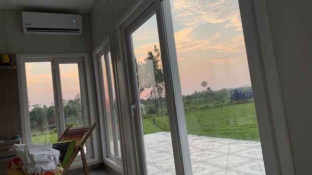 A room with large sliding glass doors leading to a patio with a tiled floor and a view of a grassy area and trees. - Campo Verde Lodge (Campoverde)