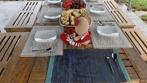 An outdoor dining setup with a table set for multiple people, surrounded by a grassy field and trees. - Campo Verde Lodge (Campoverde)
