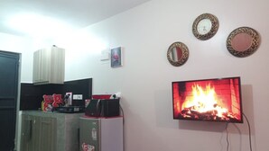 Eine Küche mit Kühlschrank, Mikrowelle und Herd. An der Wand ist ein Fernseher angebracht, der einen Kamin zeigt.