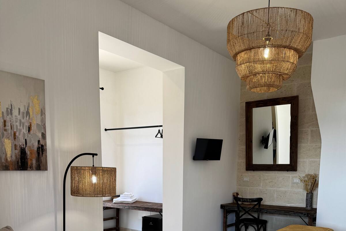 A modern living room with a sofa, a coffee table, a lamp, a TV, and a bed with a blanket.