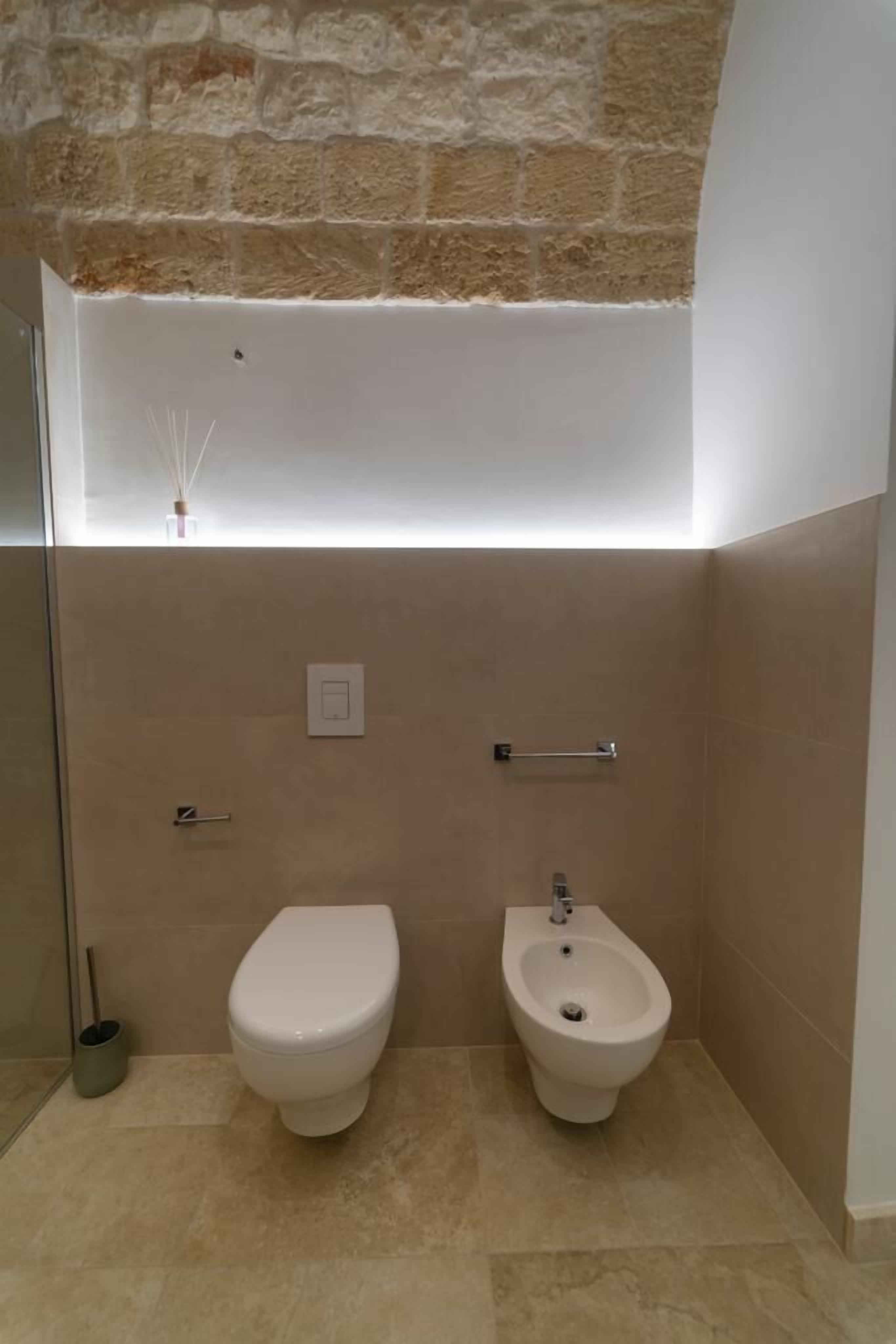 Un baño con inodoro, bidé y un perchero para toallas.
