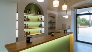A reception area with a wooden counter, green wall, and shelves of bottles. - Dimora CARASPI  (Mola di Bari)