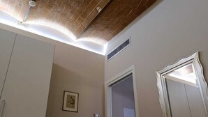 A room with a brick ceiling, a bed, a desk with a chair, a mirror, and a door. - Ultroneo locanda di collina (Vinci)
