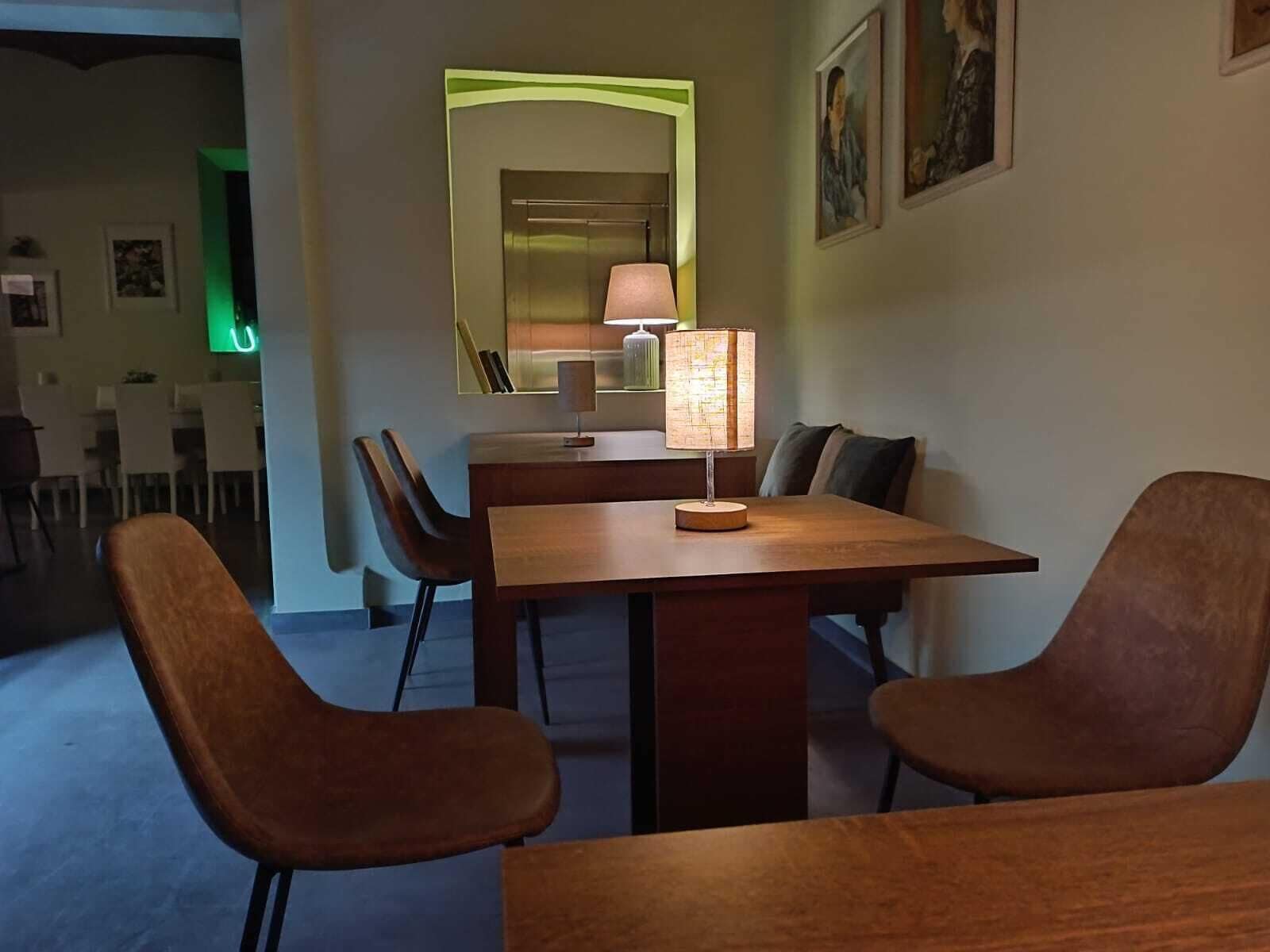 Un comedor con una mesa de madera, cuatro sillas y una lámpara de mesa.