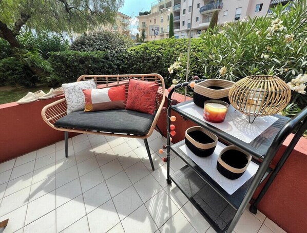A wicker sofa with cushions, a tray with candles and a lantern, and a tiled patio area.