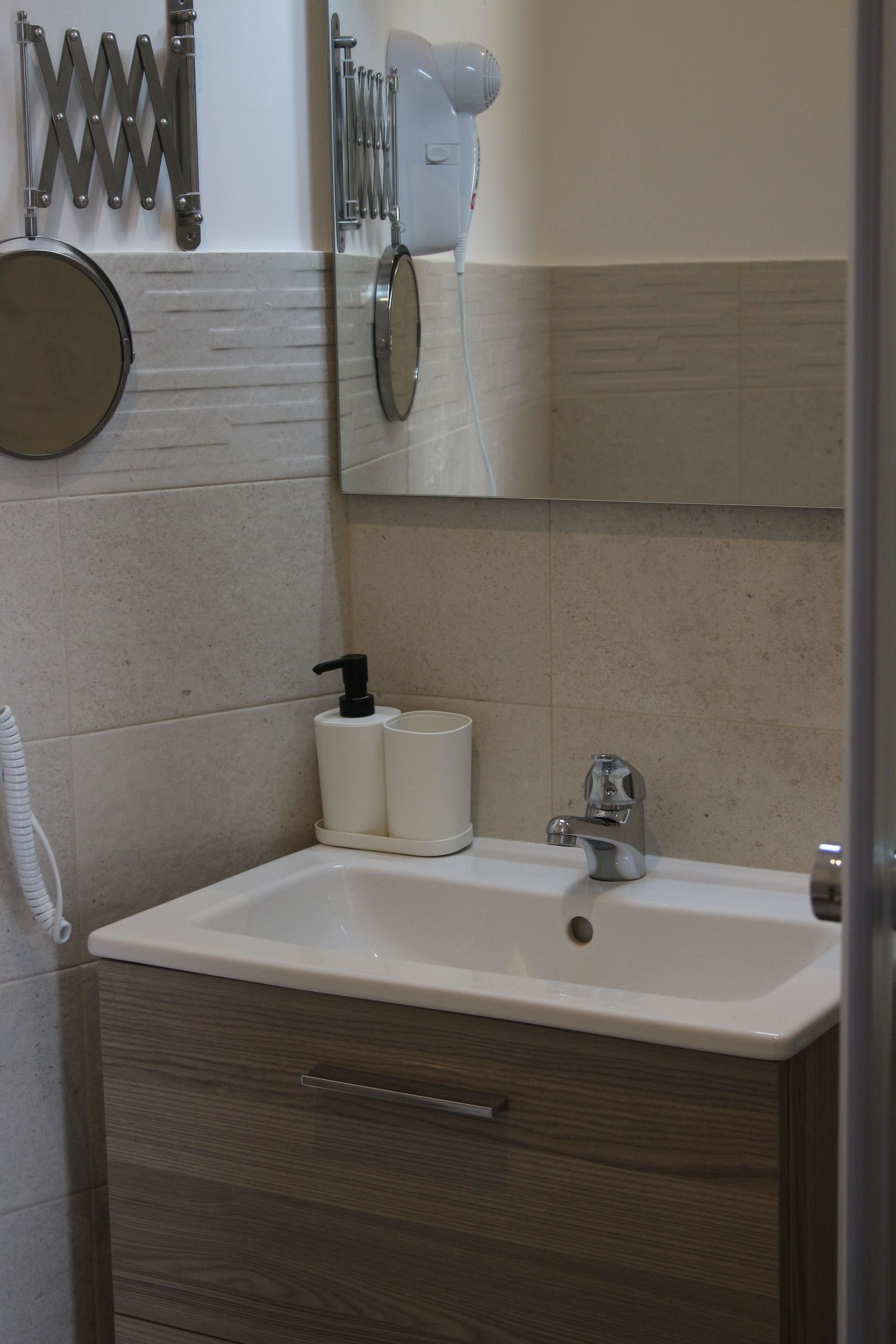 Un baño con lavamanos, espejo, toallero y artículos de aseo.