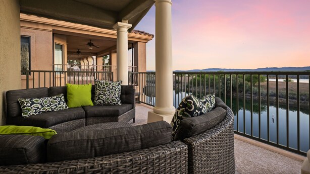 A balcony with a view of a lake, a sofa set, and a pergola structure. - 5 Bdr Beautiful Riverfront Home with Dock! (Bullhead City)