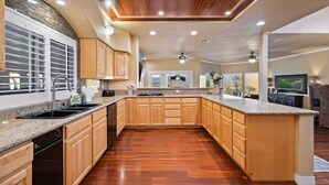 A spacious kitchen with wooden cabinets, granite countertops, and a large island. - 5 Bdr Beautiful Riverfront Home with Dock! (Bullhead City)