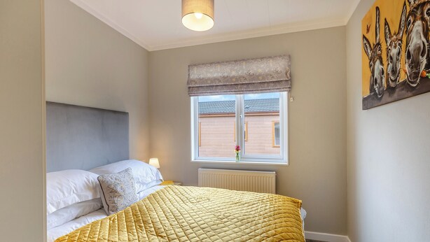 Une chambre à coucher avec un lit, une fenêtre donnant sur un paysage agréable, un radiateur et un mur décoré d’œuvres d’art.