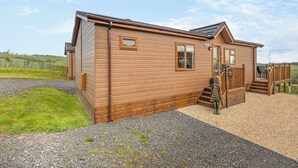 Une cabane en bois avec une véranda, un escalier et une allée gravillonnée.