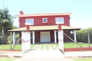 A two-story house with a red exterior, a tiled roof, and a front porch. - Recanto das Palmeiras - Clube Privativo em Meio à Mata Preservada em Atibaia (Rio Abaixo Atibaia)
