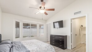 Ein Schlafzimmer mit einem Bett, einem Deckenventilator, einem Fernseher und einem Kleiderschrank.