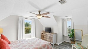 A bedroom with a bed, a television, a ceiling fan, a window, and a chair. - 3bd 2ba Sleeps 10 Golf Cart Included Pet Friendly (Panama City Beach)