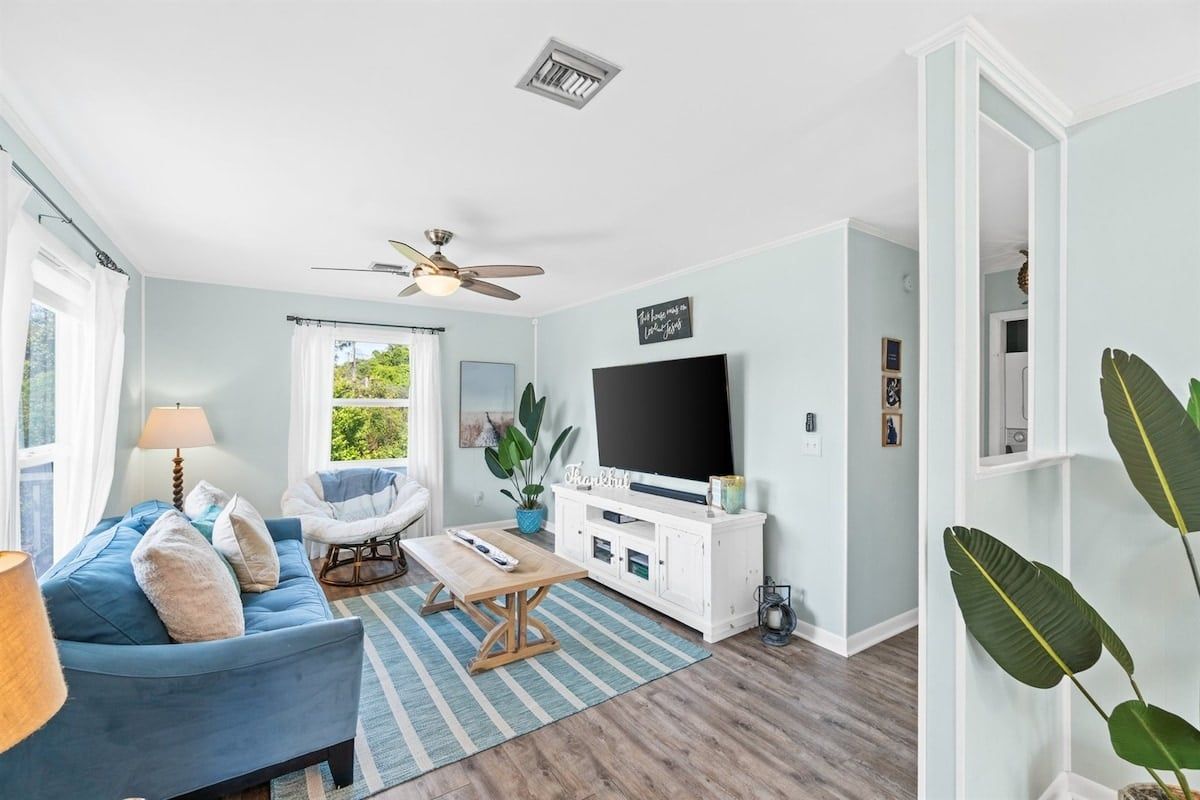 A living room with a sofa, a coffee table, a TV, and a ceiling fan.