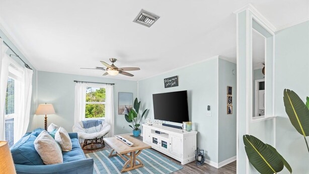 A living room with a sofa, a coffee table, a TV, and a ceiling fan. - 3bd 2ba Sleeps 10 Golf Cart Included Pet Friendly (Panama City Beach)