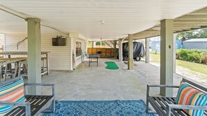 A covered patio area with outdoor furniture, a table, and a green mat. - 3bd 2ba Sleeps 10 Golf Cart Included Pet Friendly (Panama City Beach)