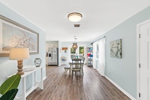 A hallway with a dining area, a ceiling light, and artwork on the walls. - 3bd 2ba Sleeps 10 Golf Cart Included Pet Friendly (Panama City Beach)