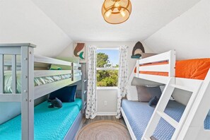 Un dormitorio con literas, una ventana con cortinas y una lámpara en el techo.