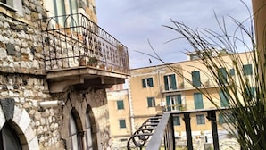 Un bâtiment en pierre doté d’un balcon, d’une plante en pot et offrant une vue sur les immeubles voisins.