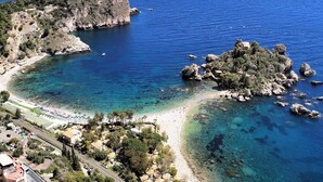 Une zone côtière dotée d’une plage, de formations rocheuses et d’eaux d’un bleu limpide.