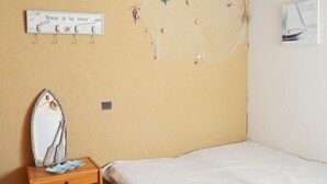 Ein Schlafzimmer mit einem Bett, einem Nachttisch mit Spiegel und einer kleinen Dekoration, einem Wandzeichen und einem Gemälde.