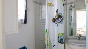 Ein Badezimmer mit Duschvorhang mit Meereslebewesen, einem Waschbecken mit Marmorplatte und einem Spiegel darüber.