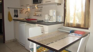 A compact kitchen with a microwave, coffee maker, and a small dining table. - 2-room apartment sleeps 4 PORT LEUCATE NATURISME (PORT LEUCATE NATURISME)