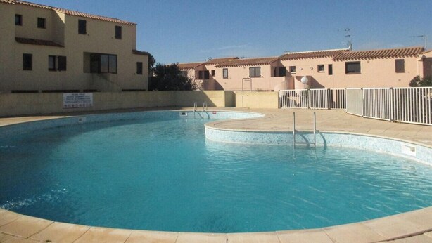 A swimming pool with a tiled deck, surrounded by buildings with a uniform architectural style. - 2-room apartment sleeps 4 PORT LEUCATE NATURISME (PORT LEUCATE NATURISME)