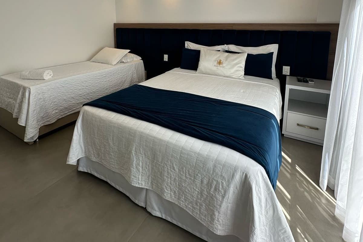 A hotel room with two beds, a nightstand, and a window with curtains.