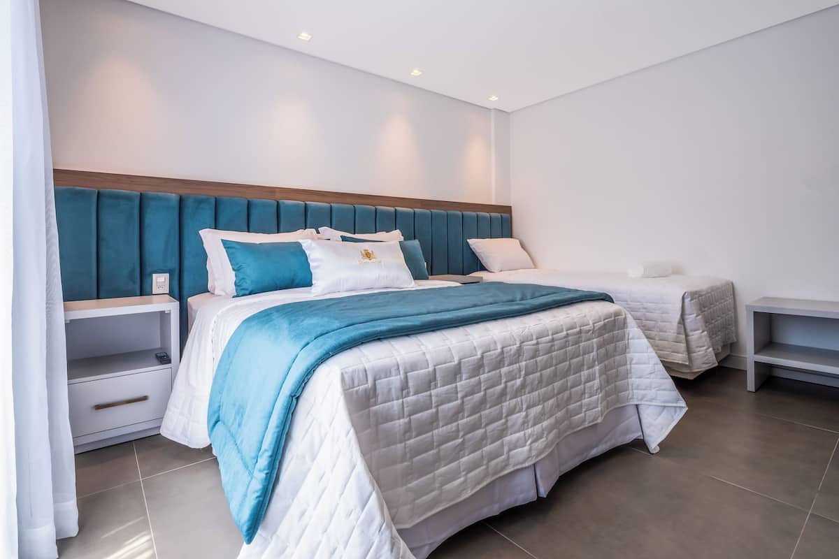 A modern hotel room with a large bed, a bedside table, and a nightstand.