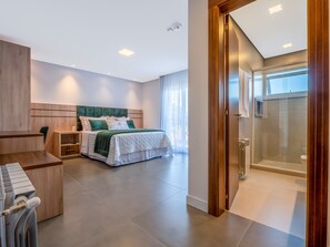 A modern bedroom with a large bed, a desk, and a shower area.
