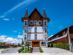 Un edificio de varios pisos con una entrada central, una estructura similar a una torre a la izquierda y un edificio de techo plano a la derecha.