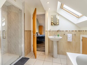 A modern bathroom with a shower, sink, and bathtub, a skylight, and a visible bedroom with a bed and wardrobe. - 5 bedroom accommodation in llanafan/Aberystwyth (llanafan/Aberystwyth)
